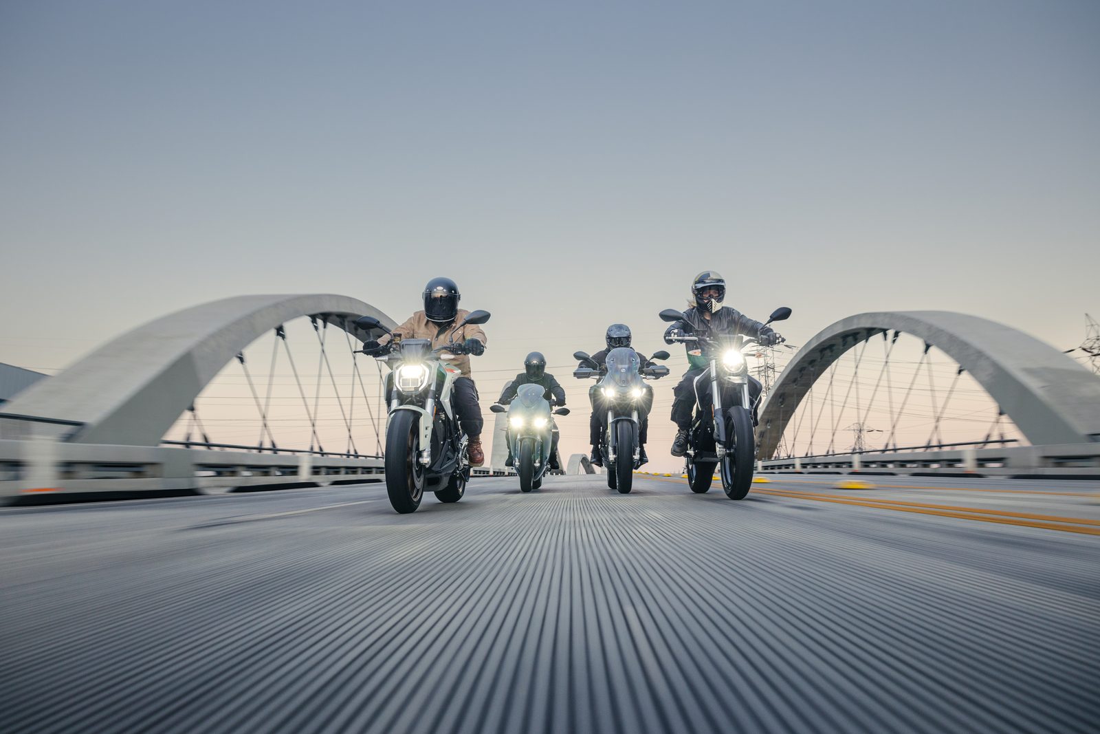 Grupo de motociclistas em motas Zero numa ponte ao entardecer